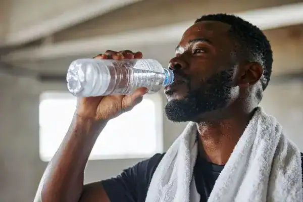 Image of man drinking water to improve hydration Broxburn after work out.